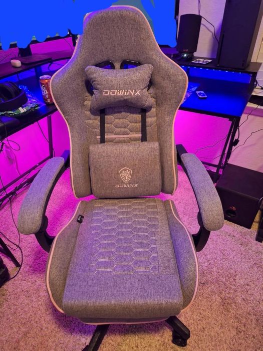 Ergonomic gaming chair with lumbar support, perfect for both office and gaming spaces, placed in a tech-filled room with shelves in the background