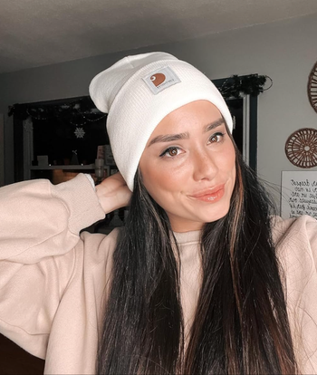 A reviewer wearing a white beanie, looking stylish and cozy.