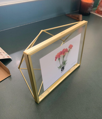 A gold frame with a geometric wire design at the back.