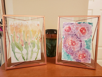 Rose gold frames featuring the same geometric pattern, holding floral art inside.