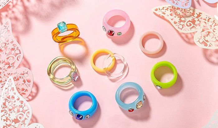 The 10 rings from the set arranged neatly on a pink background