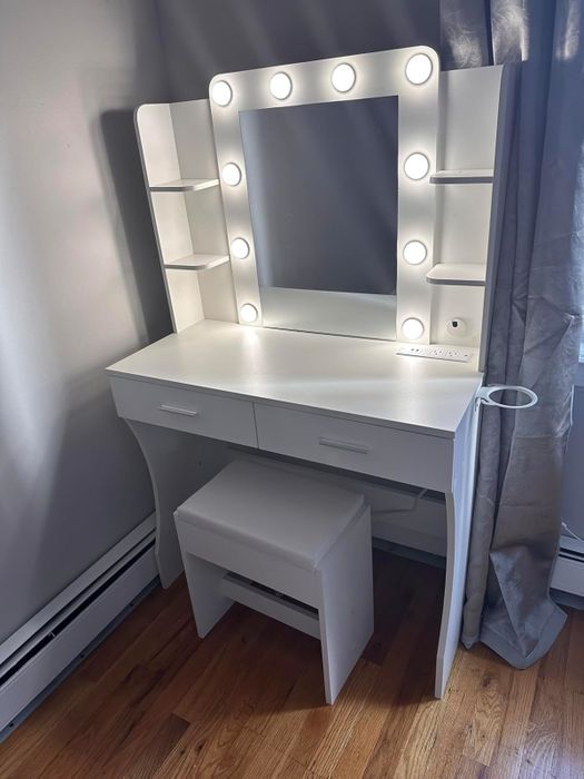 Vanity table with a lighted mirror and side shelves, paired with a matching stool. Perfect for organizing and applying makeup