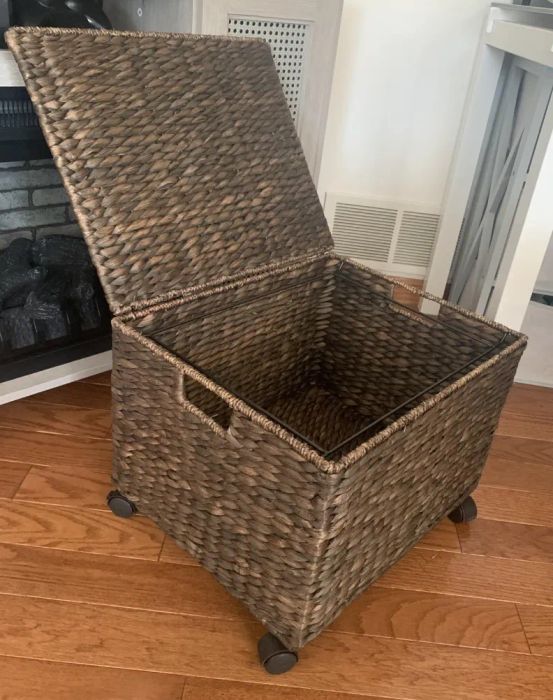 wicker storage basket on wheels with the lid open, placed in a living room, great for shopping needs and home organization