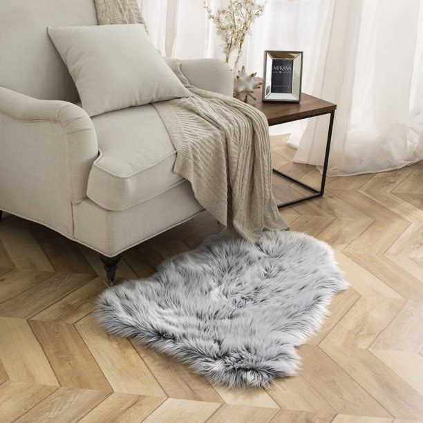 A soft gray faux-fur sheepskin rug placed next to an armchair.