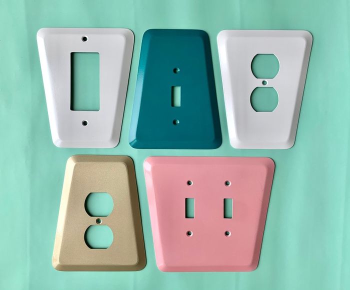A vintage-style wall plate with cutouts designed for various light switch configurations.