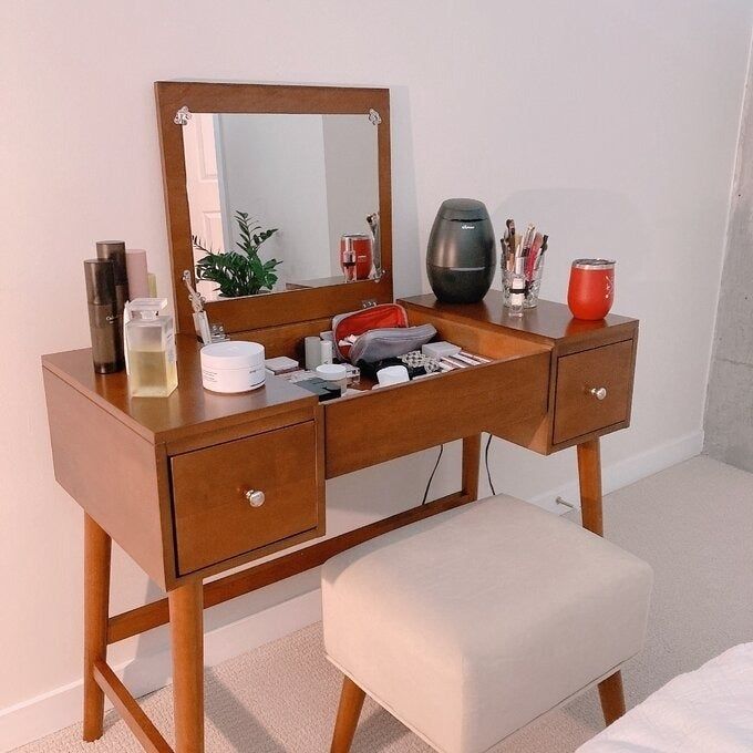 Vanity table equipped with a mirror, makeup, and skincare essentials, paired with a cushioned stool. Ideal for elevating your daily beauty regimen