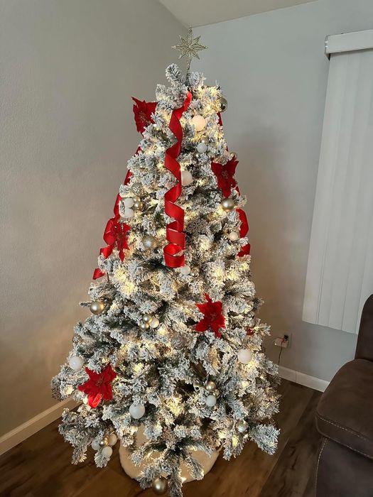 a reviewer’s elegant white flocked tree adorned with twinkling lights and vibrant red ribbon