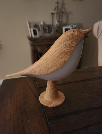 A small, light wood bird-shaped lamp displayed on a table.
