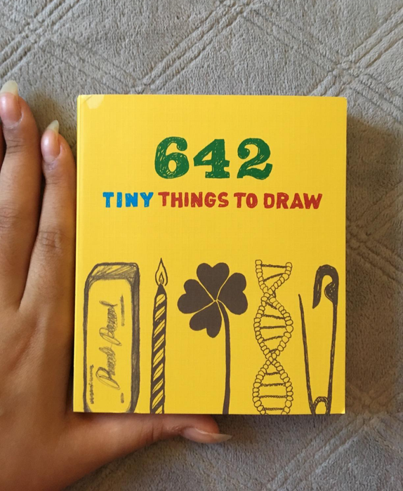 A hand placed next to the book to show its size 