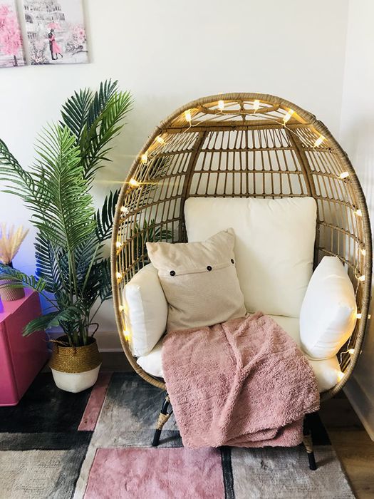 A reviewer displays the chair adorned with lights and decorative pillows