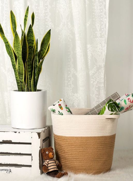 A two-tone white and brown woven basket filled with blankets in a cozy room