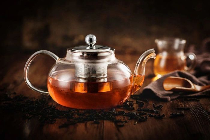 The glass teapot and infuser filled with freshly brewed tea.