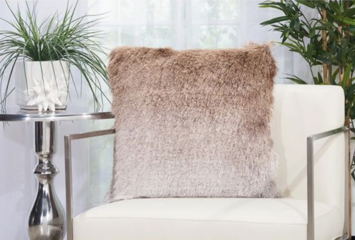 A beige ombre shag pillow resting on a sleek white chair
