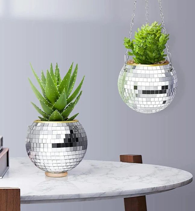 The disco ball planter resting on a table, also suspended by chains