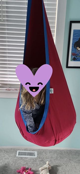 A reviewer shares a photo of their kid (with a heart graphic covering their face) lounging in a hanging hammock chair.