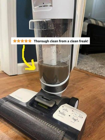 A reviewer's dirty water reservoir with text showing how much grime the Tineco 2-in-1 mop and vacuum picks up.