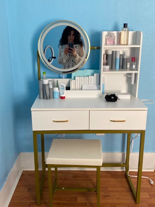 A woman capturing a selfie in the mirror above a neatly arranged vanity filled with skincare and beauty essentials