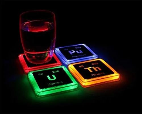 The coasters glowing on a table in a dark room, casting a soft light.
