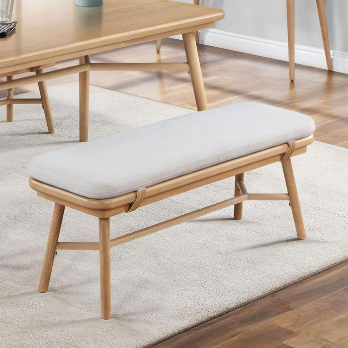 A modern wooden bench with a cushioned seat, set in a dining room to highlight its minimalist design aesthetic.