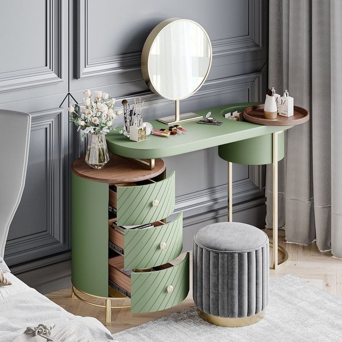 Vanity set with a round mirror, green drawers, and makeup items displayed on top, paired with a soft, round, gray stool