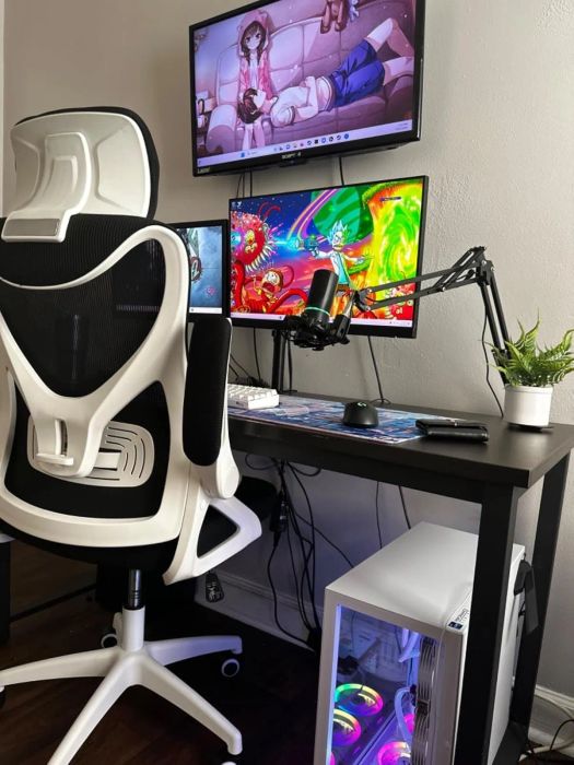 Gaming setup featuring a spacious chair, dual monitors playing anime, a professional microphone, and a neatly placed small plant on the desk