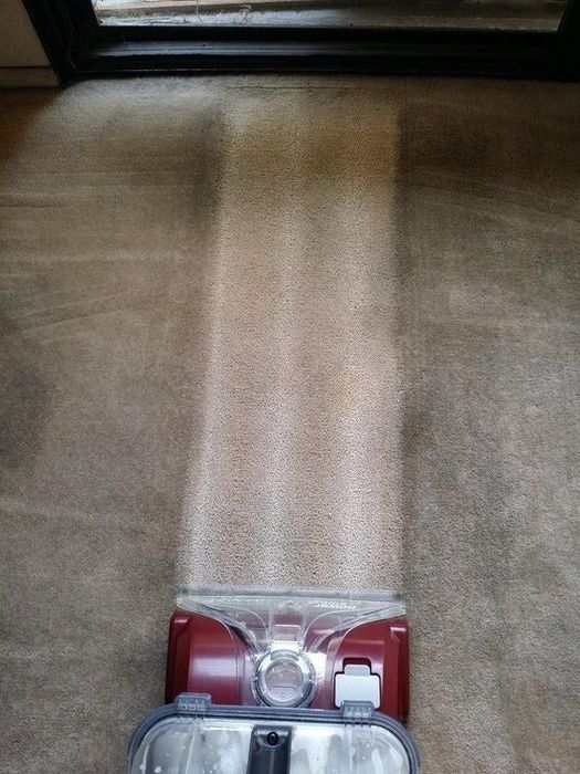 A review image showing the cleaner's path on a dirty carpet — the area behind the machine looks significantly cleaner and lighter.