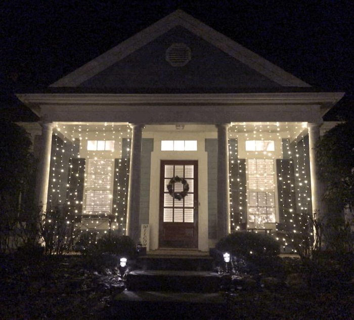 reviewer photo showcasing two string light panels glowing between columns on their front porch