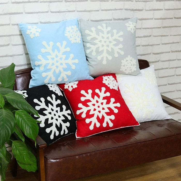 five pillowcases in various colors, each adorned with fluffy white snowflakes