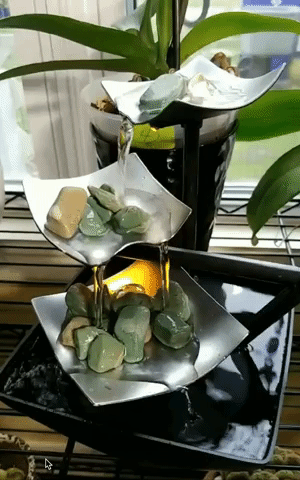 A gif showing water flowing gently down a three-tiered waterfall.