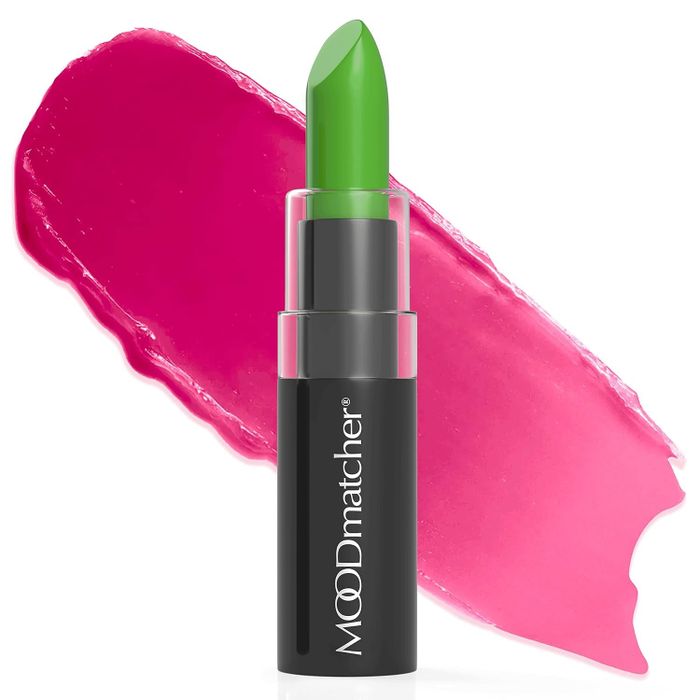 A green lipstick in a Moodmatcher tube, with a pink smear behind it, showcasing its color-changing ability for personalized shopping.