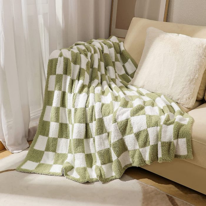 A green and white checkered throw blanket casually draped over a couch.