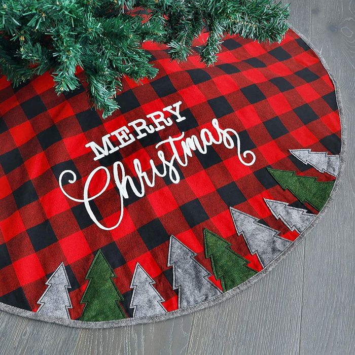 A red and black plaid tree skirt with gray and green trees adorning the bottom and 