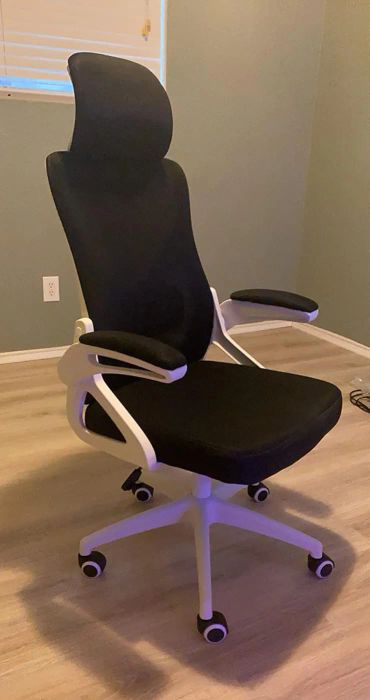 Sleek ergonomic office chair with adjustable armrests and a high backrest on wheels, set in a stylish room with wooden floors