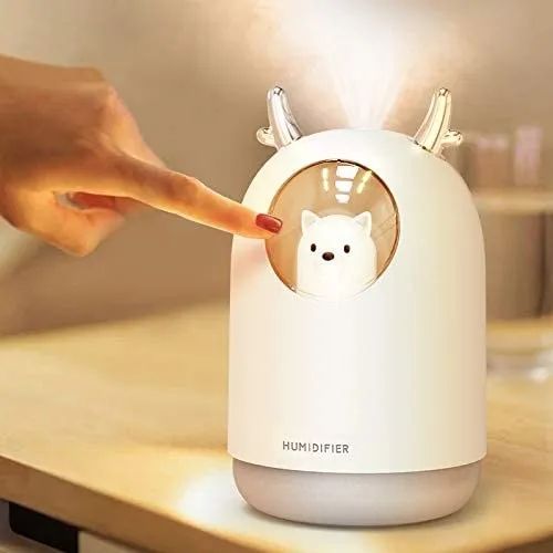A person interacting with the white cool mist humidifier by touching it.
