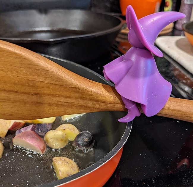 A reviewer’s photo of a purple witch-shaped spoon holder perched on a wooden spoon