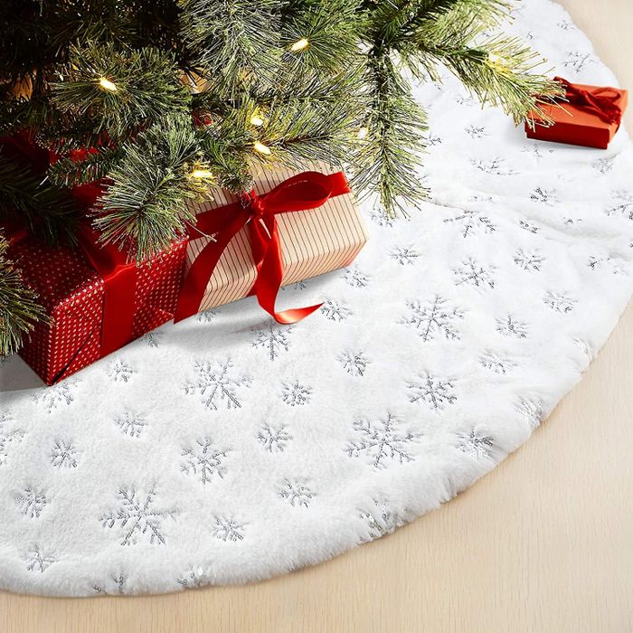 A white plush faux fur tree skirt adorned with shimmering silver snowflakes