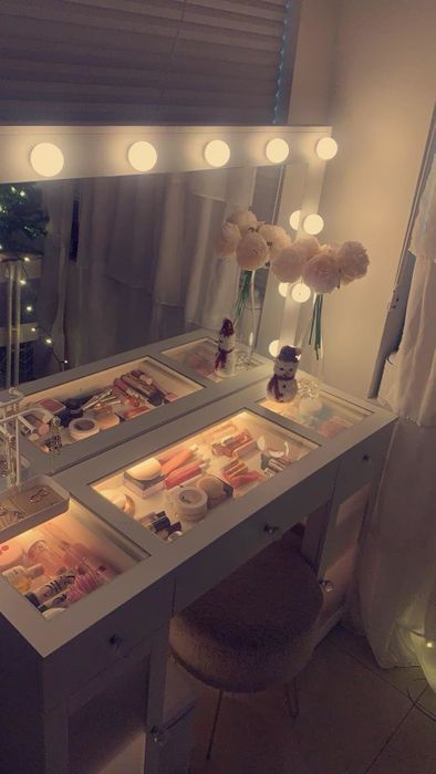 Vanity table with a lighted mirror, neatly arranged makeup, and decorative floral accents in a tranquil setting, perfect for inspiring beauty enthusiasts