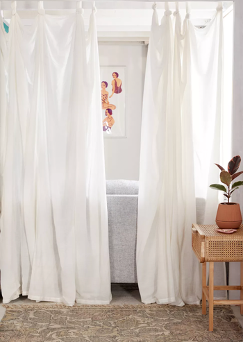 The same curtain in white, gracefully hanging next to a couch.