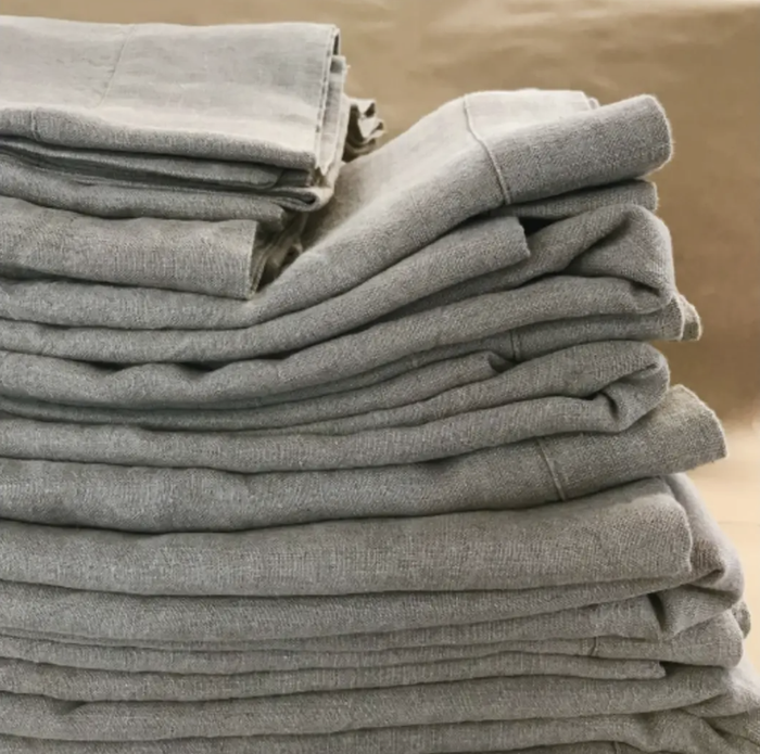 A stack of neatly folded light grey linen sheets