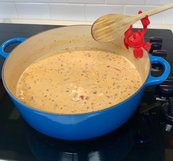 reviewer photo of a vibrant red crab spoon rest positioned beside a pot, holding a wooden spoon