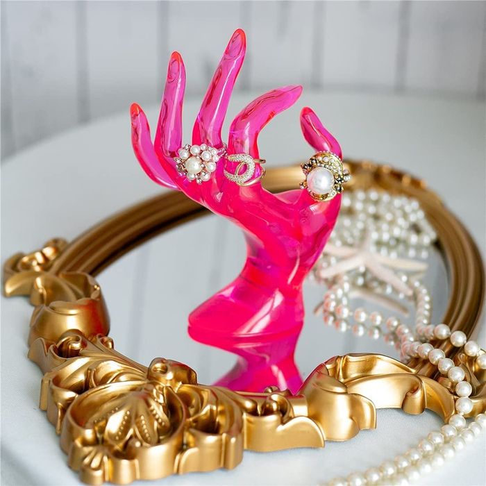 A neon pink mannequin hand serving as a unique jewelry holder