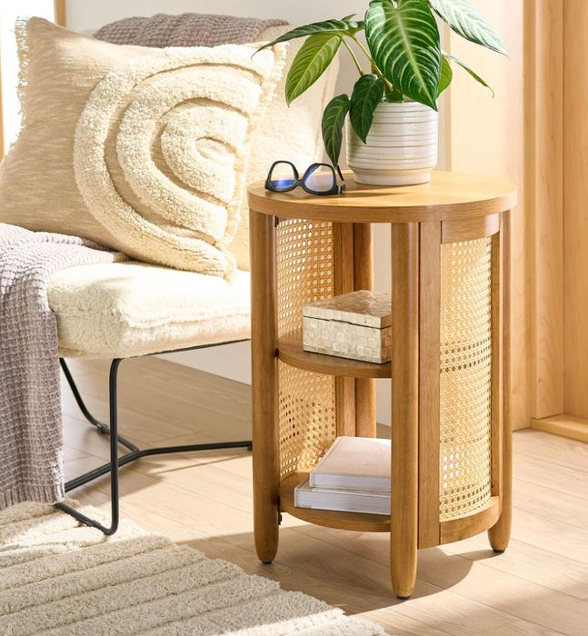A side table featuring books, a small plant, glasses, and a decorative pillow, all placed within a warm and inviting room setting.