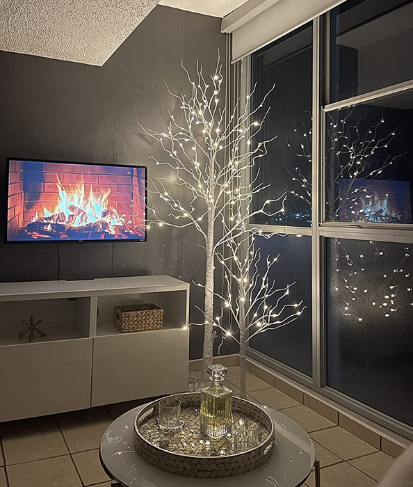 A reviewer's photo featuring two of the illuminated trees in their cozy living room