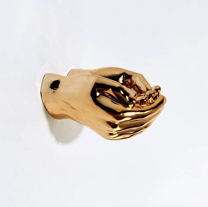 A pair of golden hand sculptures are mounted on a wall