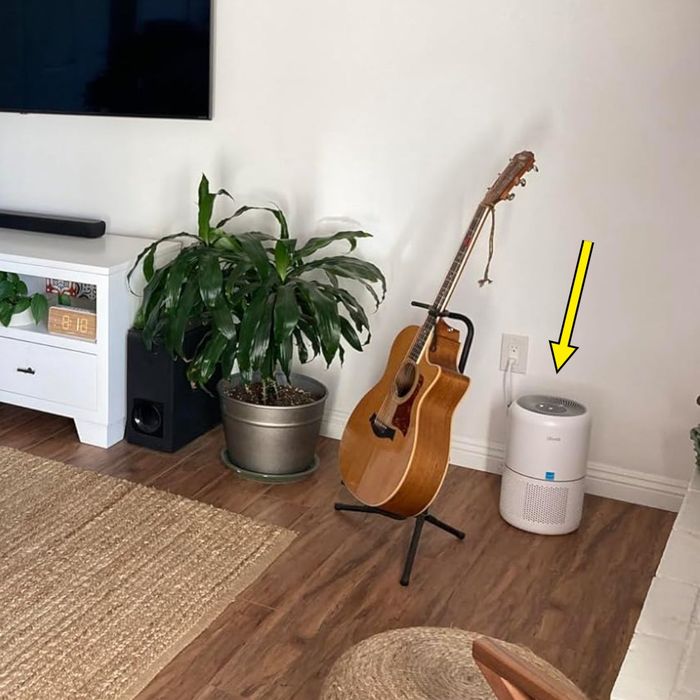 A reviewer's living room featuring an air purifier in the corner, pointed out by an arrow
