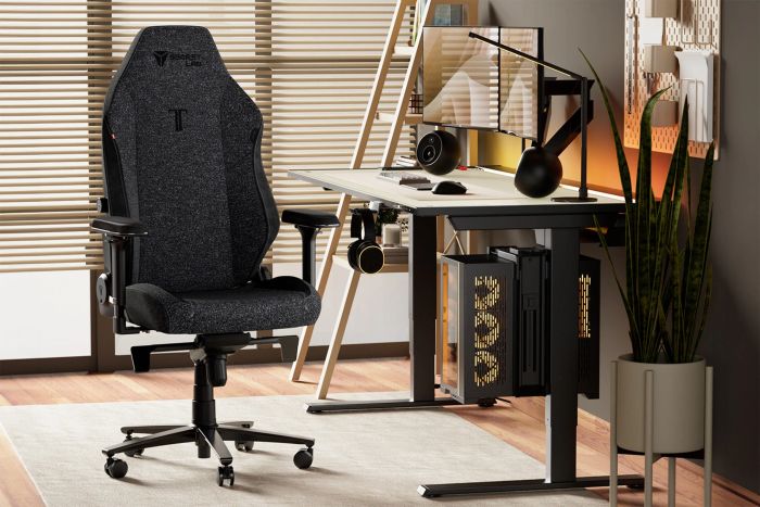 Modern home office setup featuring an ergonomic gaming chair, adjustable desk, monitor, keyboard, and headphones