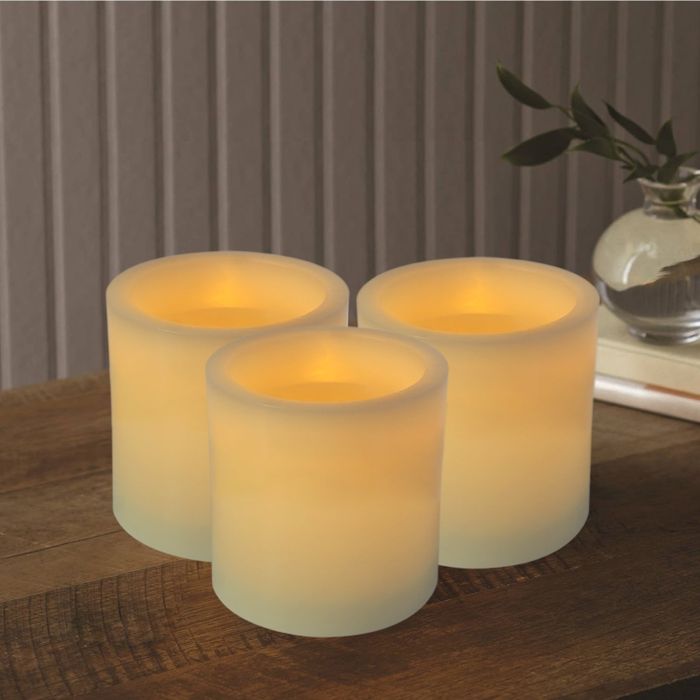 A set of four off-white pillar candles glowing gently, creating a serene, fire-free ambiance.
