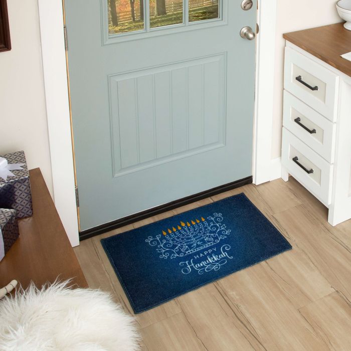 A menorah-themed doormat positioned outside a door to showcase its dimensions.
