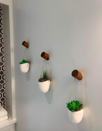 The reviewer uses the same wall hooks to elegantly display hanging succulents on a corner wall.