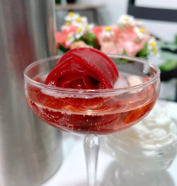 A red rose-shaped ice cube floating in a cocktail
